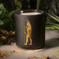 Black candle with a gold design in a natural setting
