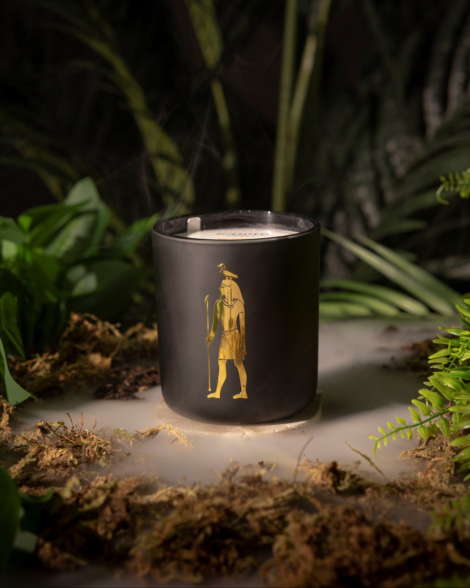 Black candle with a gold design in a natural setting